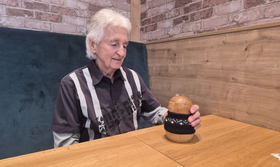 Eine ältere Person und eine kleine Holzfigur schauen sich an