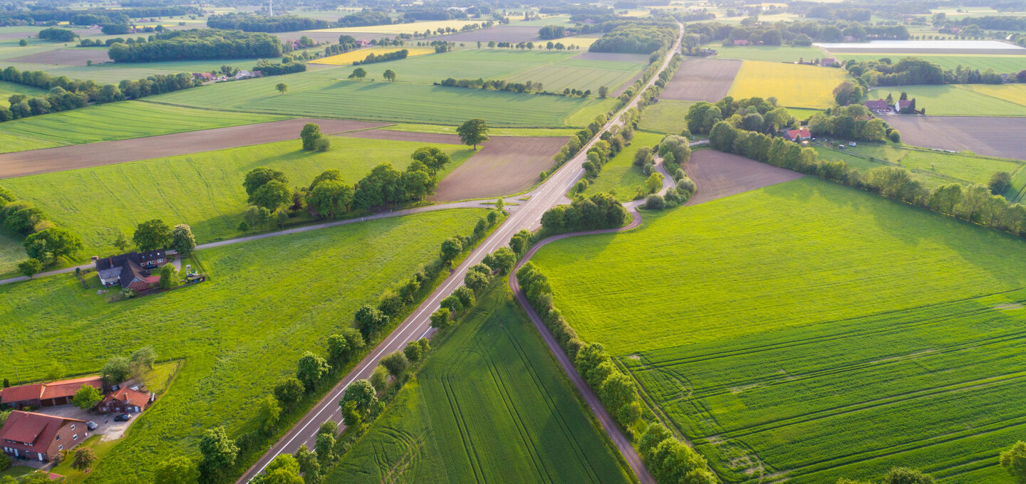 Luftaufnahme einer Ackerlandschaft mit einer Landstraße