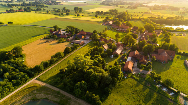 Ländliche Landschaft mit Feldern und Bauernhäusern bei Sonnenuntergang